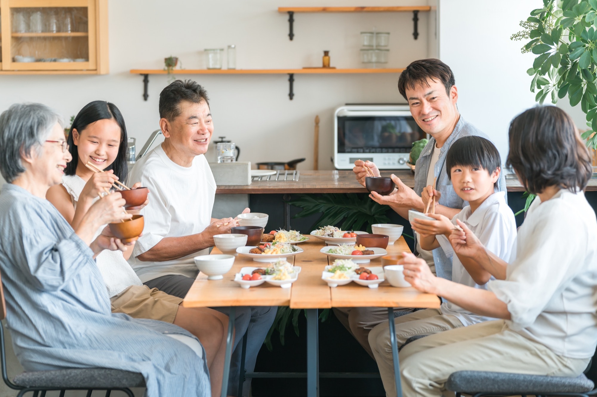 家で食事する三世代家族